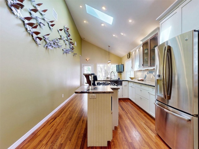 536 Faulkner St, New Smyrna Beach, FL 32168 - kitchen featuring high vaulted ceiling, a skylight, wood finished floors, glass insert cabinets, and stainless steel refrigerator with ice dispenser