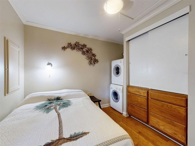 536 Faulkner St, New Smyrna Beach, FL 32168 - bedroom with light wood-style flooring, ornamental molding, stacked washing maching and dryer, and ceiling fan