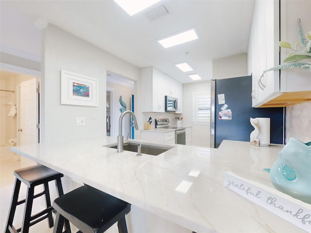 2700 N Peninsula Ave Unit 114, New Smyrna Beach, FL 32169 - kitchen featuring white cabinetry, a sink, a kitchen breakfast bar, and appliances with stainless steel finishes