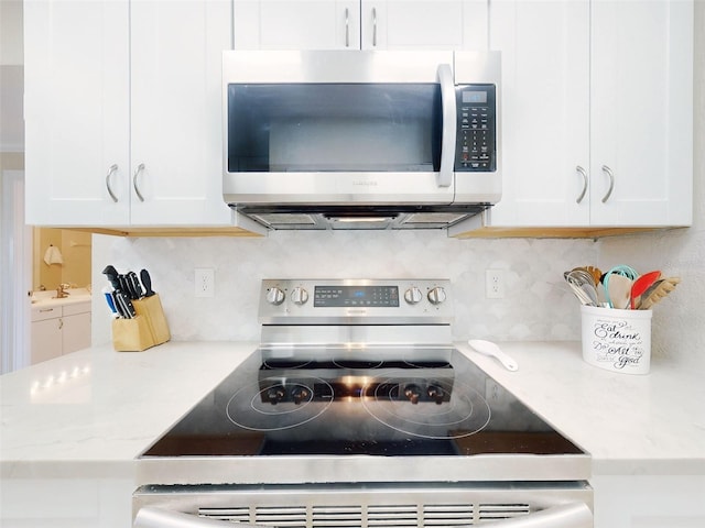 2700 N Peninsula Ave Unit 114, New Smyrna Beach, FL 32169 - kitchen featuring white cabinets, stainless steel appliances, and tasteful backsplash