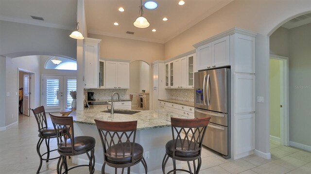 2904 Palma Ln, New Smyrna Beach, FL 32168 - kitchen with stainless steel refrigerator with ice dispenser, a sink, arched walkways, tasteful backsplash, and white cabinetry