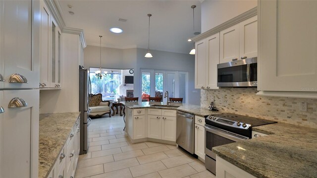 2904 Palma Ln, New Smyrna Beach, FL 32168 - kitchen with stainless steel appliances, a sink, a peninsula, tasteful backsplash, and light stone counters