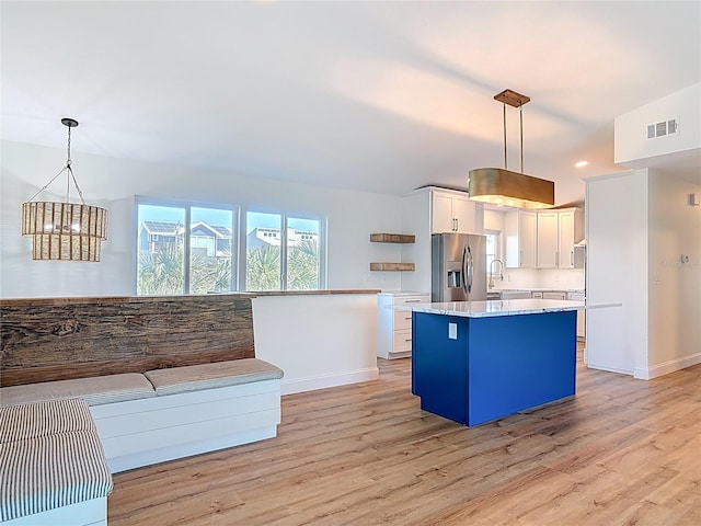 6937 Turtlemound Rd, New Smyrna Beach, FL 32169 - kitchen featuring stainless steel refrigerator with ice dispenser, a center island, light wood finished floors, white cabinets, and recessed lighting