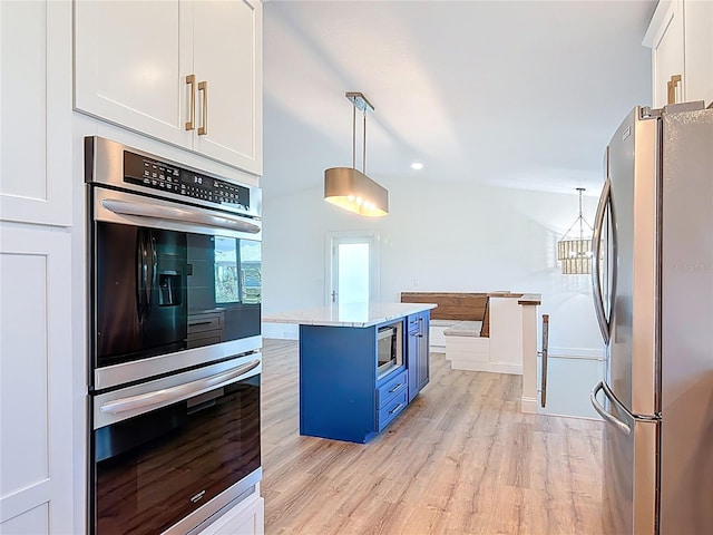6937 Turtlemound Rd, New Smyrna Beach, FL 32169 - kitchen featuring stainless steel appliances, white cabinets, light wood-style floors, pendant lighting, and blue cabinets