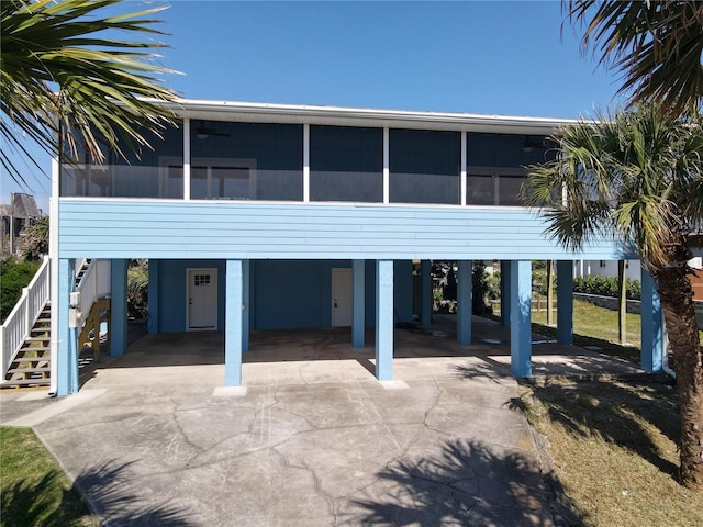 6937 Turtlemound Rd, New Smyrna Beach, FL 32169 - view of front facade with concrete driveway, a sunroom, stairway, and a carport