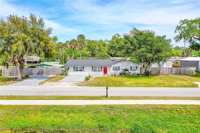view of front of property with a front yard, concrete driveway, and fence