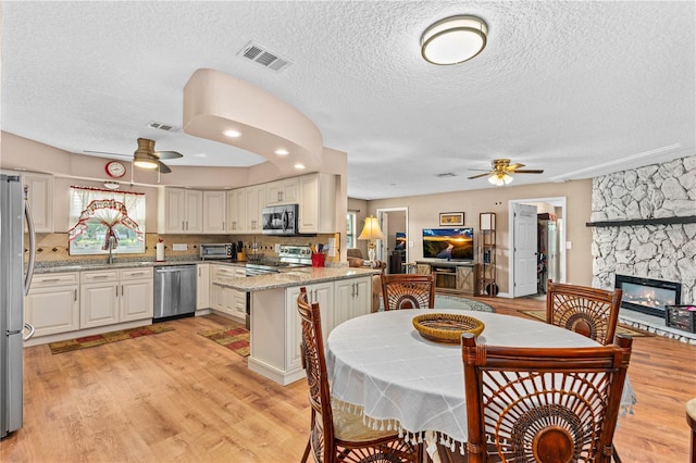 kitchen featuring open floor plan, visible vents, ceiling fan, and stainless steel appliances