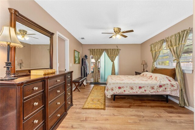 bedroom featuring baseboards, a ceiling fan, visible vents, and light wood-type flooring