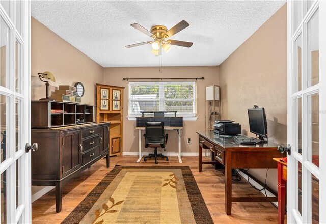 office space featuring a textured ceiling, baseboards, wood finished floors, a ceiling fan, and french doors