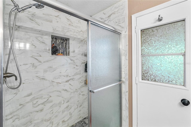 full bath with a textured ceiling and a shower stall
