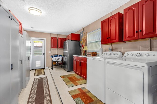 laundry room with independent washer and dryer, cabinet space, and a textured ceiling