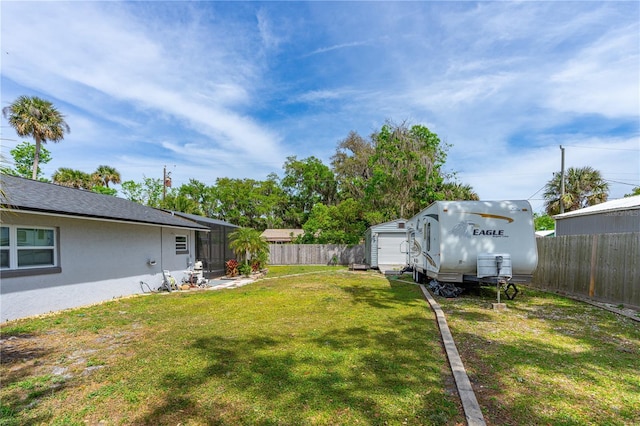 view of yard with a garage, a fenced backyard, an outdoor structure, and a shed