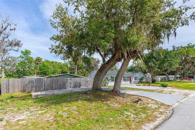 view of yard featuring fence and concrete driveway