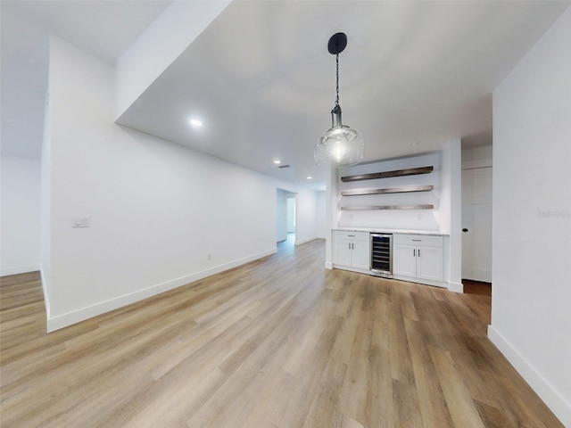 unfurnished living room with recessed lighting, baseboards, light wood finished floors, beverage cooler, and a bar