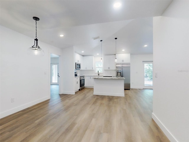 kitchen with a sink, a kitchen island, white cabinetry, appliances with stainless steel finishes, and light wood-style floors