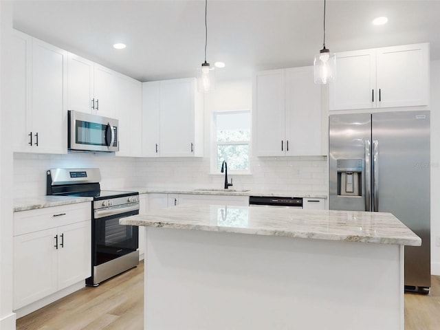 kitchen featuring a sink, stainless steel appliances, white cabinets, light wood-style floors, and decorative backsplash