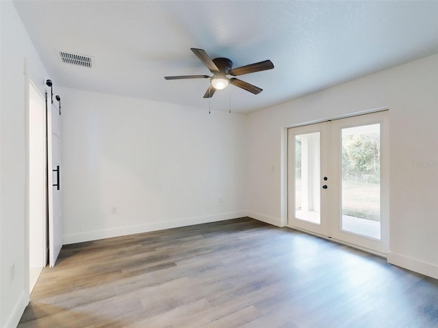 spare room with a ceiling fan, wood finished floors, baseboards, and visible vents