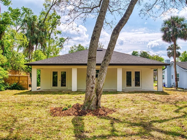 view of front of property with stucco siding, fence, french doors, and a front yard