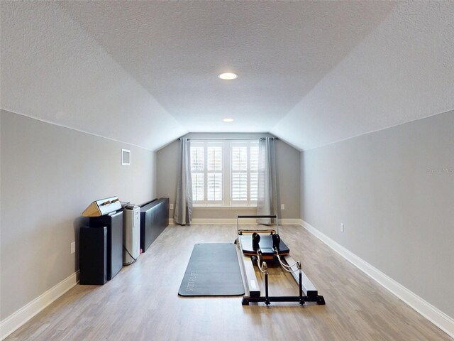 2656 Old Smyrna Trl, New Smyrna Beach, FL 32168 - exercise room featuring baseboards, vaulted ceiling, light wood-style flooring, and a textured ceiling