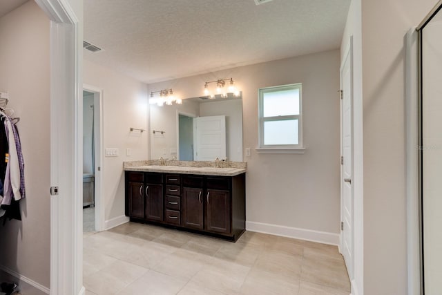 208 Lagoon Mist Ct, Oak Hill, FL 32759 - bathroom with baseboards, double vanity, a textured ceiling, and a sink