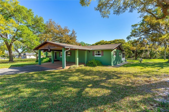 191 Howes St, Oak Hill, FL 32759 - view of front of house featuring an attached carport, a front yard, stucco siding, and aphalt driveway