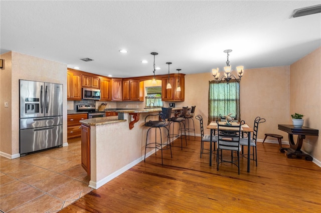 191 Howes St, Oak Hill, FL 32759 - kitchen featuring a peninsula, visible vents, a chandelier, stainless steel appliances, and brown cabinets