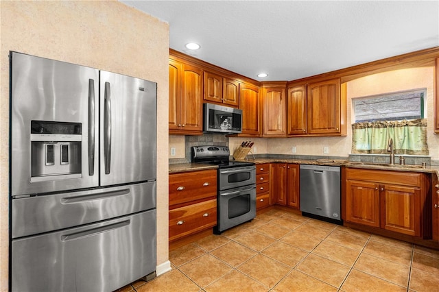 191 Howes St, Oak Hill, FL 32759 - kitchen with brown cabinetry, appliances with stainless steel finishes, light tile patterned floors, and a sink