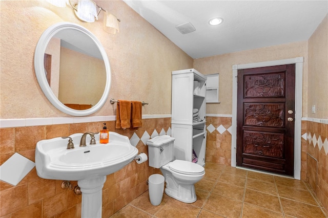 191 Howes St, Oak Hill, FL 32759 - bathroom featuring tile walls, toilet, tile patterned flooring, and a wainscoted wall