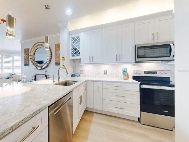 438 Bouchelle Dr Unit 104, New Smyrna Beach, FL 32169 - kitchen with a sink, white cabinetry, appliances with stainless steel finishes, decorative backsplash, and ornamental molding