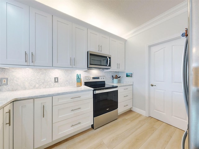 438 Bouchelle Dr Unit 104, New Smyrna Beach, FL 32169 - kitchen with crown molding, light wood finished floors, white cabinetry, stainless steel appliances, and decorative backsplash