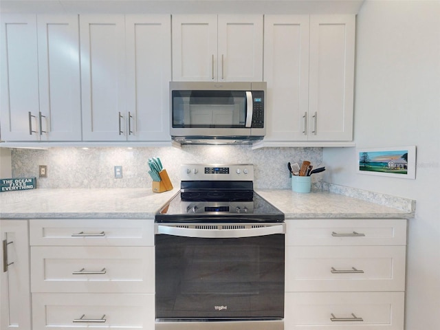 438 Bouchelle Dr Unit 104, New Smyrna Beach, FL 32169 - kitchen featuring white cabinetry, light stone counters, decorative backsplash, and appliances with stainless steel finishes