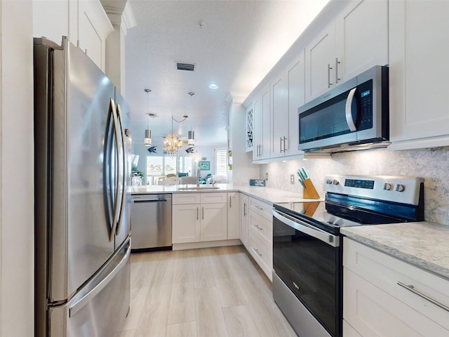 438 Bouchelle Dr Unit 104, New Smyrna Beach, FL 32169 - kitchen with a sink, appliances with stainless steel finishes, visible vents, white cabinets, and decorative backsplash