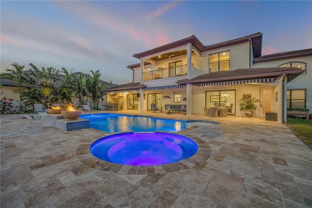 1212 Commodore Dr, New Smyrna Beach, FL 32168 - back of house at dusk featuring stucco siding, a patio, an in ground hot tub, and a balcony