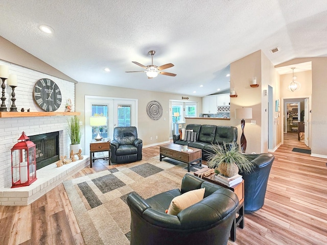 living room with a textured ceiling, wood finished floors, a ceiling fan, and vaulted ceiling