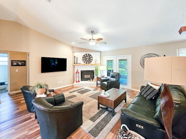 living room featuring wood finished floors, baseboards, a ceiling fan, and vaulted ceiling