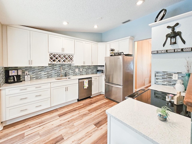 kitchen featuring tasteful backsplash, a sink, light wood-style floors, white cabinetry, and stainless steel appliances