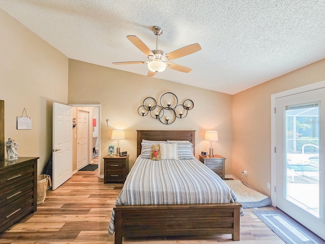 bedroom with light wood-style floors, access to exterior, multiple windows, and vaulted ceiling
