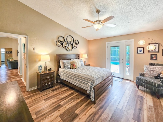 bedroom featuring a textured ceiling, wood finished floors, lofted ceiling, and access to exterior