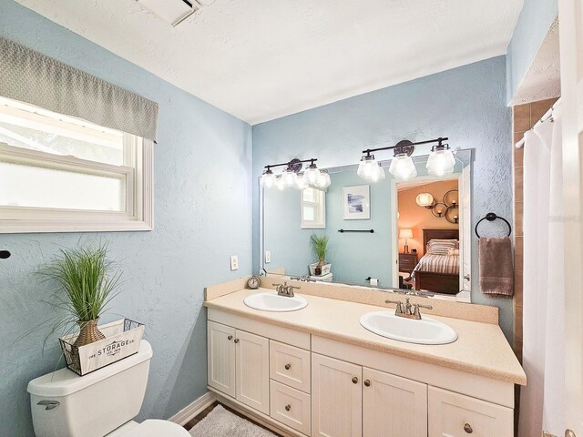 ensuite bathroom with a sink, ensuite bathroom, toilet, and double vanity