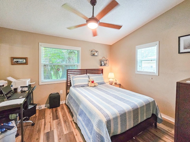 bedroom with a textured ceiling, wood finished floors, and lofted ceiling