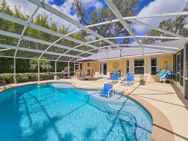 outdoor pool with a patio and glass enclosure