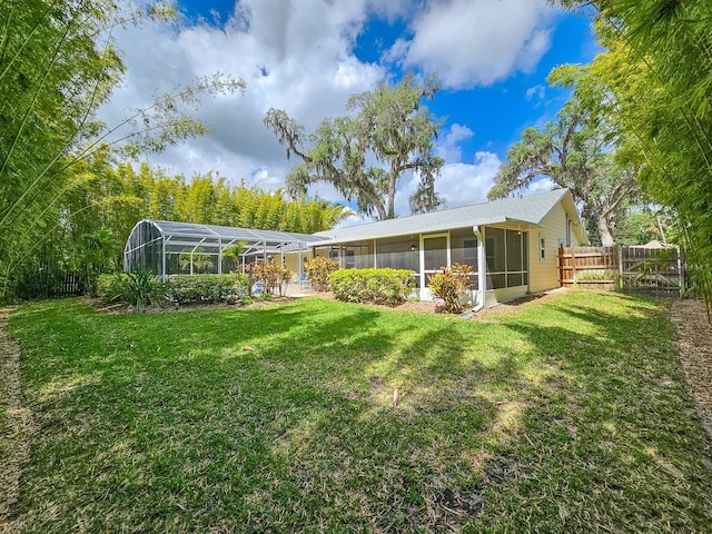 rear view of property featuring a yard, fence, and a lanai
