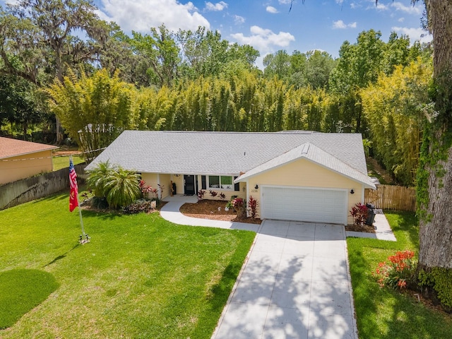 ranch-style home with a shingled roof, an attached garage, fence, concrete driveway, and a front lawn
