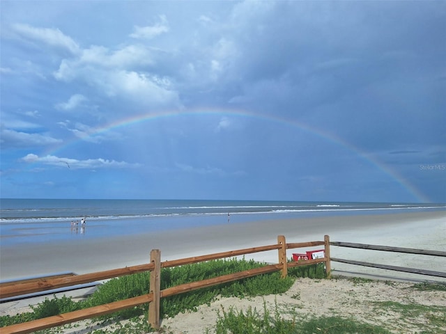 view of water feature featuring fence and a view of the beach