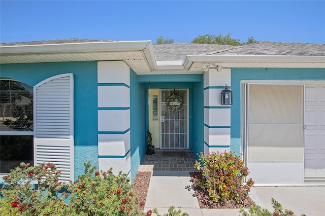 doorway to property with a shingled roof and stucco siding