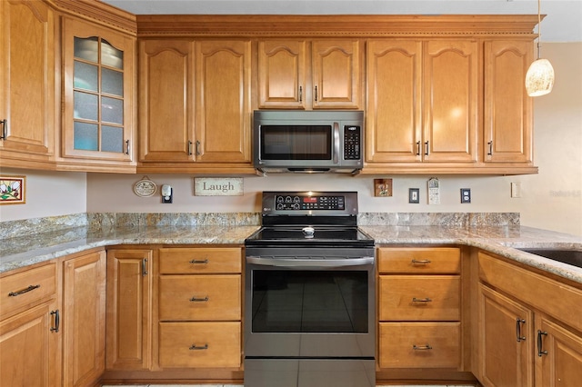 kitchen with appliances with stainless steel finishes, tile patterned flooring, light stone counters, and glass insert cabinets