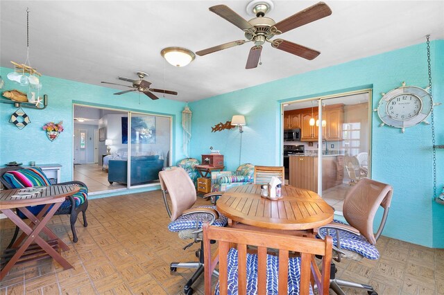dining space with a textured wall and ceiling fan