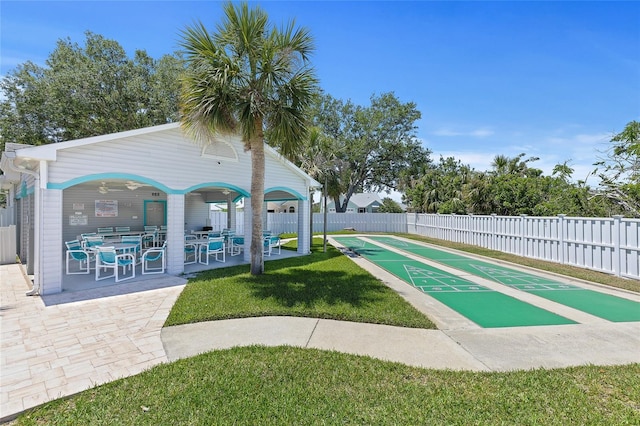 surrounding community with fence, a lawn, and shuffleboard