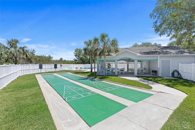 view of property's community featuring a lawn, fence, and shuffleboard