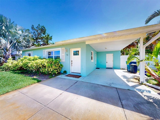 16 Hillside Dr, New Smyrna Beach, FL 32169 - view of front facade with concrete driveway, a carport, and stucco siding